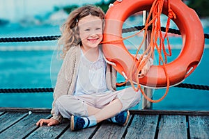 Happy child girl with rescue ring with sea background, safety on the water concept