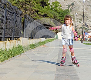 Happy child girl roller skating on natural background