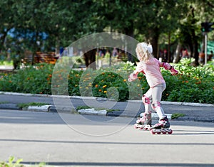 Happy child girl roller skating on natural background