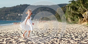 Happy child girl running on beach by sea in summer