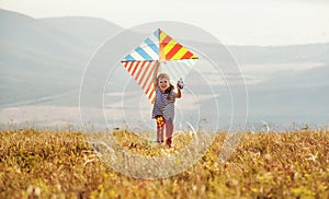Happy child girl running with kite at sunset outdoors