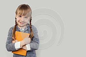 Happy child girl in school uniform clothes with book on white background. Back to school, elementary school lesson and education