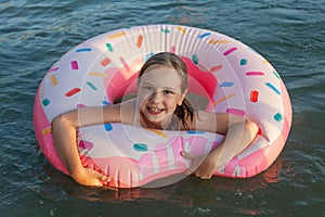 Happy child girl in the sea. Kid with swimming ring smiling