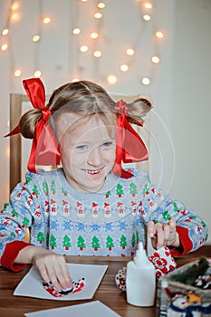 Happy child girl in seasonal sweater making Christmas post cards