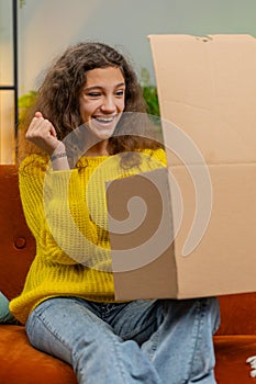 Happy child girl shopper unpacking cardboard box delivery parcel online shopping purchase at home