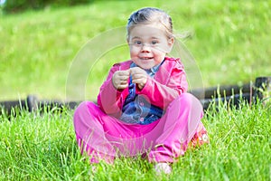 Happy child girl sitting on green grass