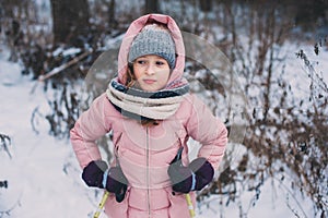 Happy child girl skiing in winter snowy forest, spending holidays outdoor.