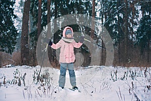 Happy child girl skiing in winter snowy forest, spending holidays outdoor.