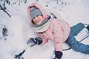 Happy child girl skiing in winter snowy forest, spending holidays outdoor.