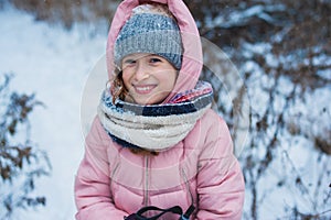 Happy child girl skiing in winter snowy forest, spending holidays outdoor.