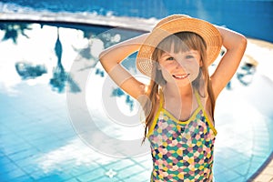 Happy child girl smiling, blue water of swimming pool. Summer vacation concept