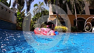 Happy child girl swimming in the pool in summer day. Family summer vacation.