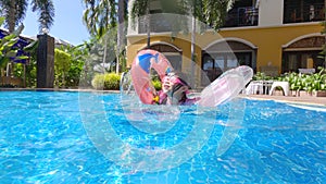 Happy child girl swimming in the pool in summer day. Family summer vacation.