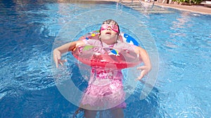 Happy child girl swimming in the pool in summer day. Family summer vacation.