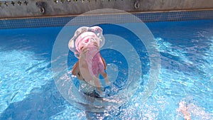 Happy child girl swimming in the pool in summer day. Family summer vacation.