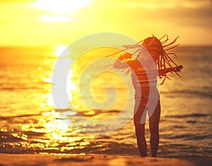 Happy child girl in swimsuit with flying hair dancing on beach at sunset