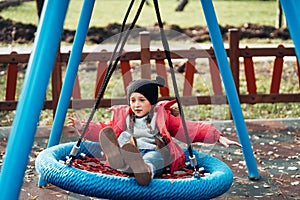 Happy child girl on swing. Little kid playing in the autumn pack.