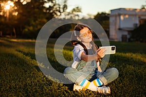 happy child girl take a selfie by mobile phone outdoors in nature green park
