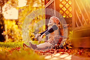 Happy child girl throwing leaves on the walk in sunny autumn garden photo