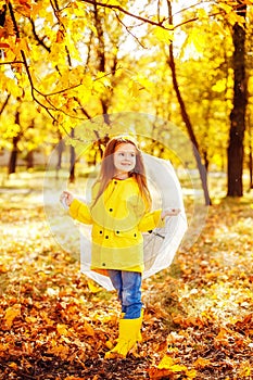 Happy child girl with an umbrella and rubber boots an autumn walk