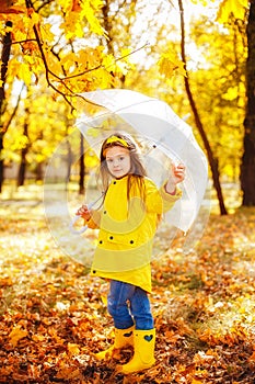 Happy child girl with an umbrella and rubber boots an autumn walk