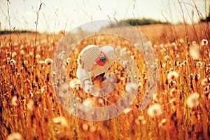 Happy child girl walking on summer meadow with dandelions. Rural country style scene, outdoor activities