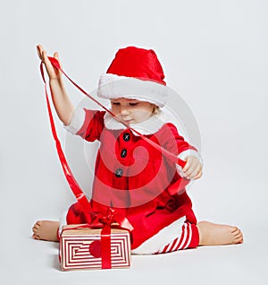 Happy child girl wearing Santa hat opening Christmas gift box