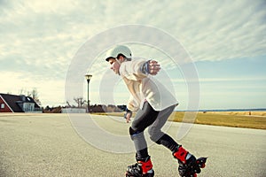 Happy child girl in white helmet, inline skates and safety equipment having fun during skating at sunny day