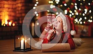 Happy child girl writing letter santa home near Christmas tree