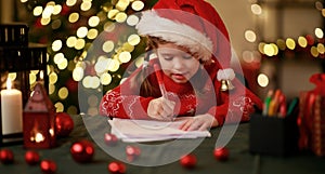 Happy child girl writing letter santa home near Christmas tree