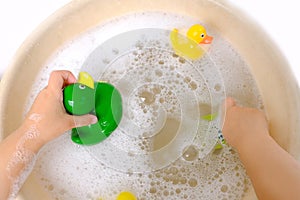 happy child, girl 3 years old plays with rubber green, yellow ducks for swimming, child's toy in soapy foam