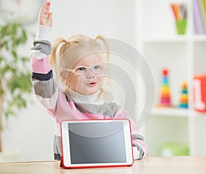 Happy child in glasses with hand up and tablet pc photo