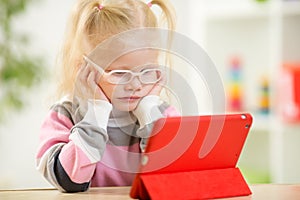 Happy child in glasses looking at mini tablet pc photo