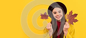 happy child in hat and coat with autumn maple leaves on yellow background. Autumn fall child for poster design. Banner