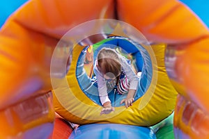 A happy child is having fun on a children`s game inflatable colorful trampoline. A little girl is playing on the playground. A chi