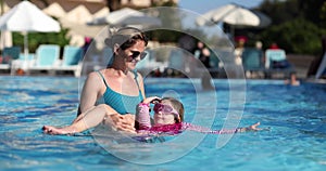 Happy child having fun mother and daughter in swimming pool