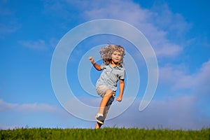 Happy child having fun outdoors. Kid playing in summer park. Little boy running on green fresh grass field. Children