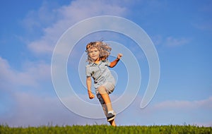 Happy child having fun outdoors. Kid playing in summer park. Little boy running on green fresh grass field. Children
