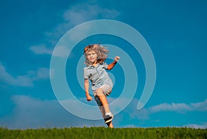 Happy child having fun outdoors. Kid playing in summer park. Little boy running on green fresh grass field. Children