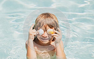 Happy child having fun at swimming pool on summer day. Children playing in blue sea water. Funny kids face. Covered eyes