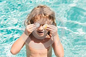 Happy child having fun at swimming pool on summer day. Children playing in blue sea water. Tropical summer vacation