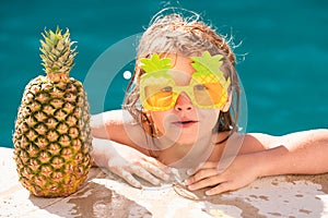 Happy child having fun at swimming pool on sunny day. Kids summer holidays and vacation concept. Summer pineapple fruit.
