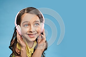Happy child in headphones listening favorite music in studio