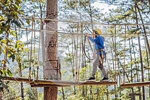 Happy child in a helmet, healthy teenager school boy enjoying activity in a climbing adventure park on a summer day