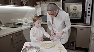 Happy child with his happy mother prepare Easter cookies together, prepare for the holiday, positive emotions