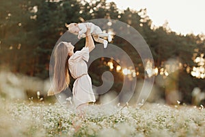 Happy child and his mom have fun outdoors in a field. Mom holds the child in her arms, and the child hugs. Mother`s Day. selectiv