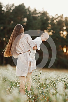 Happy child and his mom have fun outdoors in a field. Mom holds the child in her arms, and the child hugs. Mother`s Day. selectiv