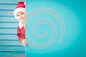 Happy child holding blue Christmas banner blank against wooden background