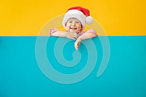 Happy child holding blue Christmas banner blank against yellow background