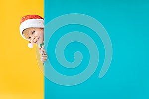 Happy child holding blue Christmas banner blank against yellow background